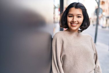 Young woman smiling confident looking to the camera at street