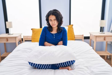 Evdeki yatakta koyu renk saçlı, kuşkucu ve gergin bir İspanyol kadın kollarını kavuşturup yüzünü onaylamıyor. negatif kişi. 