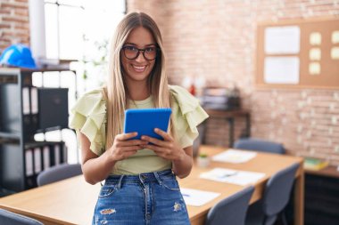 Genç, güzel, İspanyol bir iş adamı ofisteki dokunmatik pedini kullanarak gülümsüyor.