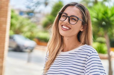 Young blonde woman wearing glasses looking to the side at street