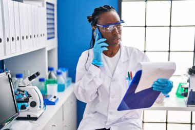 Afrikalı Amerikalı kadın bilim adamı laboratuarda belge okuyor.