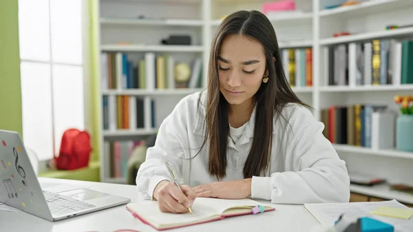 若い美しいヒスパニック女性学生使用ノートパソコン書きノートで大学教室 — ストック写真