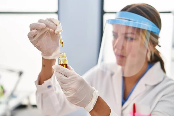 研究室で瓶に液体を注ぐ若いヒスパニック系女性科学者 — ストック写真