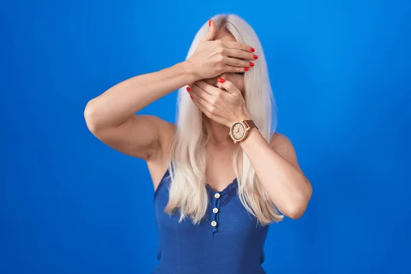 Mavi Arka Planda Duran Beyaz Kadın Gözlerini Ağzını Elleriyle Kapatıyor — Stok fotoğraf