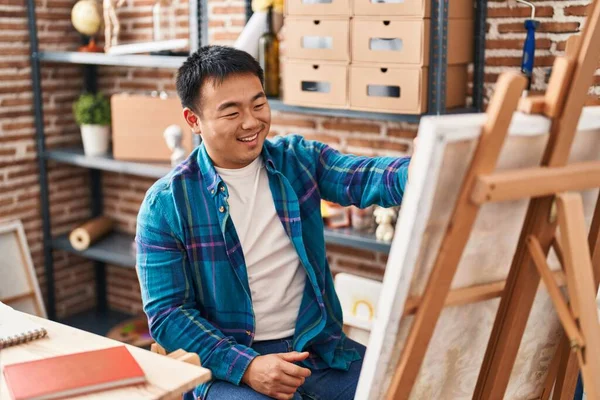 年轻的中国男艺人在画室里画画布 — 图库照片