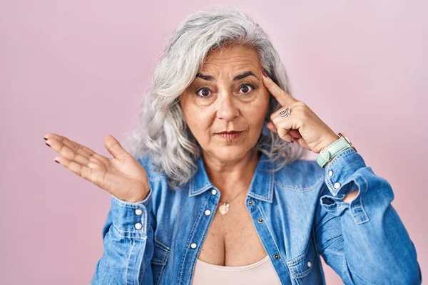 Pembe Arka Planda Duran Gri Saçlı Orta Yaşlı Bir Kadın — Stok fotoğraf