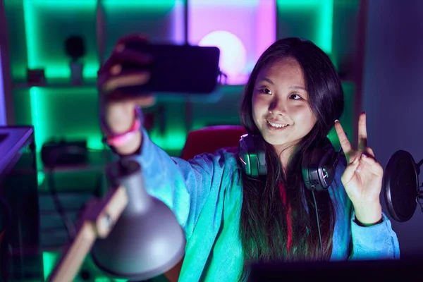 若い中国人女性ストリーマー笑顔自信を持って作る自画によってスマートフォンでゲームルーム — ストック写真
