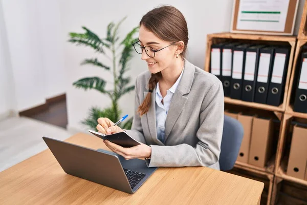 オフィスのノートパソコンでノートパソコンを使って仕事をする若い白人女性 — ストック写真