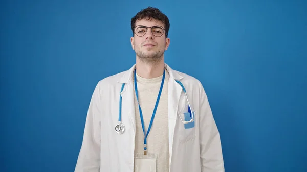 Молодий Іспаномовний Лікар Стоїть Серйозним Виразом Над Ізольованим Синім Тлом — стокове фото
