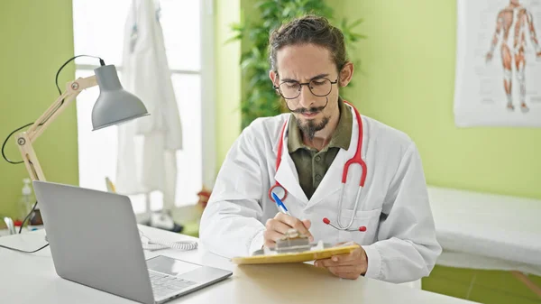 Giovane Ispanico Uomo Medico Utilizzando Laptop Scrittura Sugli Appunti Clinica — Foto Stock