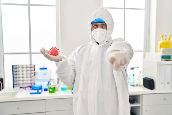 Joven Hispano Trabajando Laboratorio Científico Sosteniendo Juguete Del Virus Señalando — Foto de Stock