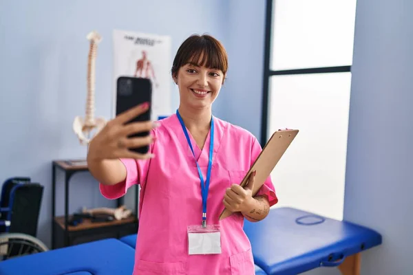 Young Beautiful Hispanic Woman Physiotherapist Make Selfie Smartphone Rehab Clinic — Fotografia de Stock