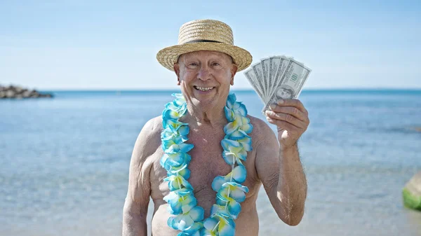 シニア白髪の男観光客身に着けています水着と夏の帽子保持ドルで海辺 — ストック写真