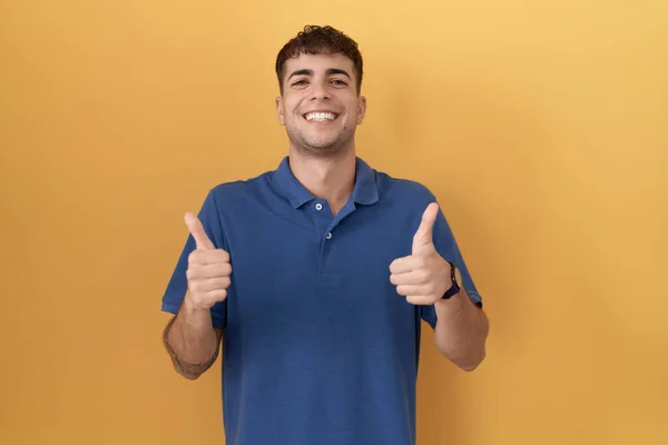 Spanyol Asıllı Genç Adam Sarı Arka Plan Başarı Işaretinin Üzerinde — Stok fotoğraf