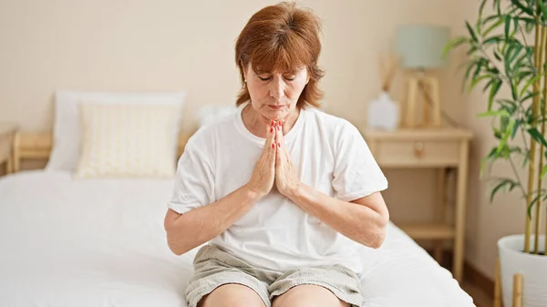 Μέση Ηλικία Γυναίκα Κάθεται Στο Κρεβάτι Προσεύχεται Στο Υπνοδωμάτιο — Φωτογραφία Αρχείου