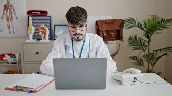 Young Hispanic Man Doctor Using Laptop Working Clinic — Φωτογραφία Αρχείου