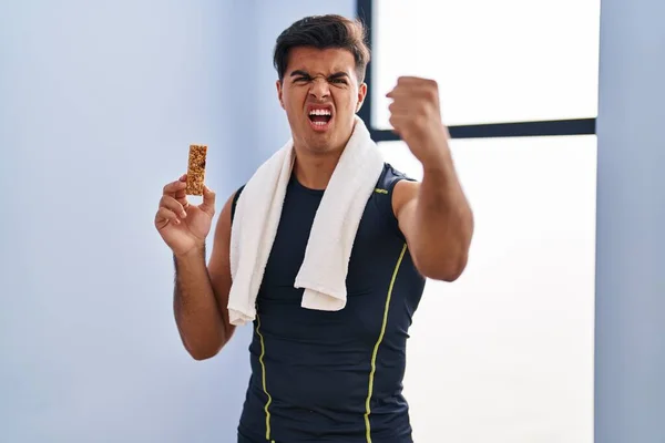 Homem Hispânico Comendo Barra Proteína Como Lanche Energia Saudável Irritado — Fotografia de Stock