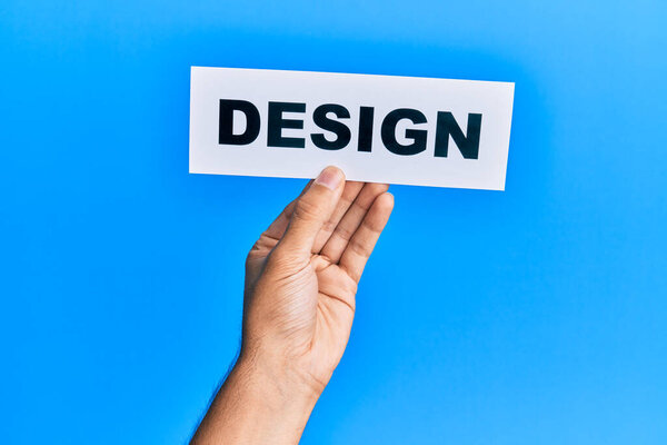 Hand of caucasian man holding paper with design word over isolated blue background