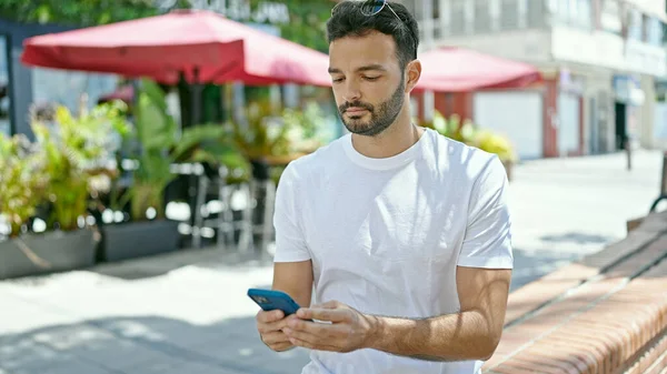 Joven Hombre Hispano Usando Smartphone Con Expresión Seria Terraza Cafetería —  Fotos de Stock