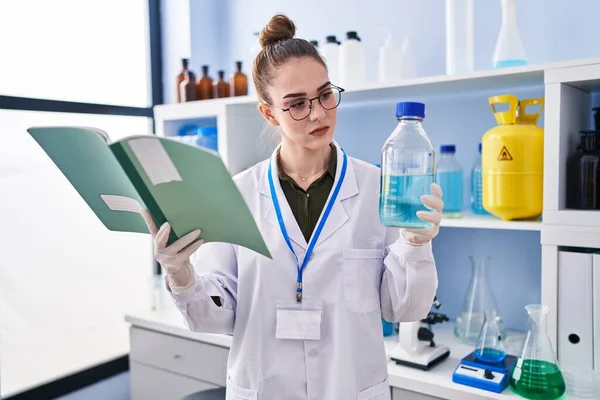 Young Woman Scientist Reading Book Holding Bottle Laboratory — Stock Photo, Image