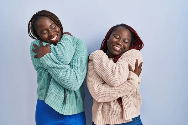青い背景の上に立っている2人のアフリカ人女性は 自分自身を幸せと肯定的に抱き 自信を笑っています 自己愛と自己ケア — ストック写真