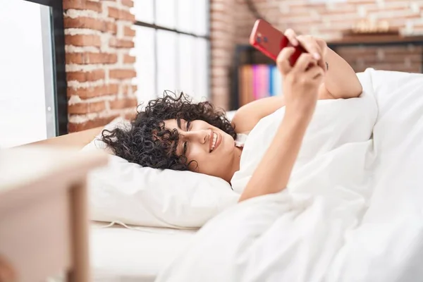 Młoda Kobieta Bliskim Wschodzie Pomocą Smartfona Leżącego Łóżku Sypialni — Zdjęcie stockowe