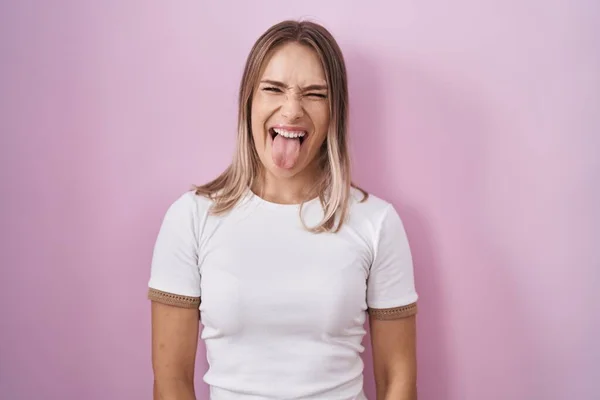 Blonďatá Běloška Stojící Nad Růžovým Pozadím Radostně Vystrkující Jazyk Legračním — Stock fotografie