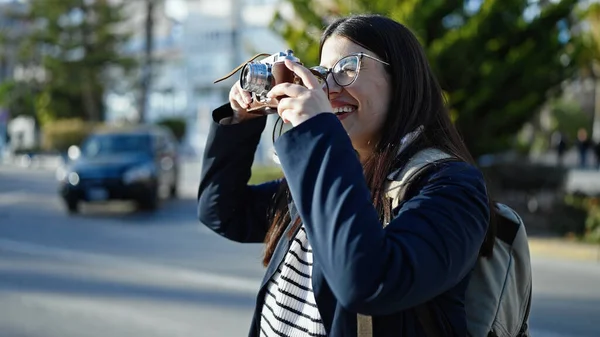 年轻的惊慌失措的女游客背着背包在街上用相机拍照 — 图库照片