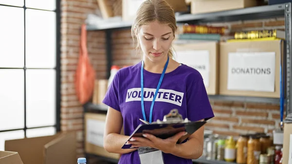 Νεαρή Ξανθιά Εθελόντρια Γράφει Λίστα Ελέγχου Στο Φιλανθρωπικό Κέντρο — Φωτογραφία Αρχείου