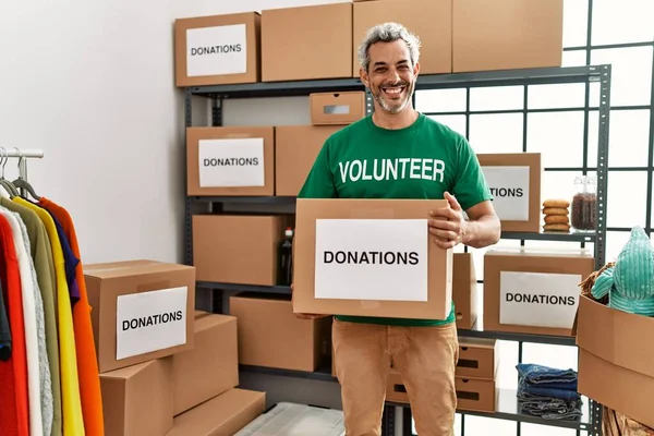 Hombre Pelo Gris Mediana Edad Voluntario Sonriendo Confiado Sosteniendo Donaciones —  Fotos de Stock