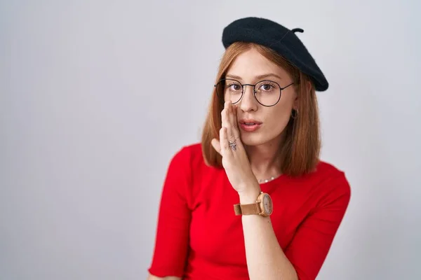 Ung Rödhårig Kvinna Stående Glasögon Och Basker Hand Mun Berättar — Stockfoto