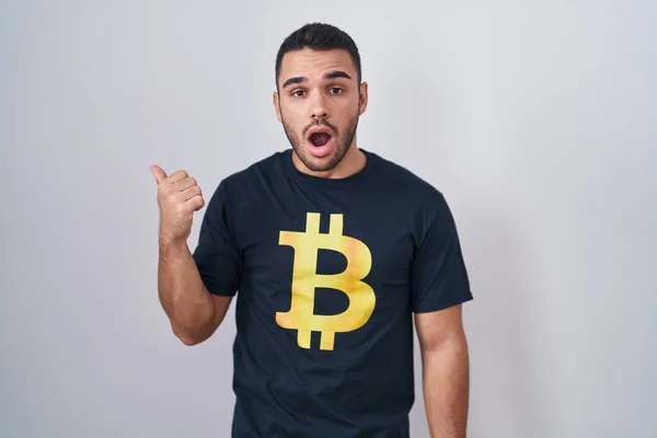 Joven Hombre Hispano Vistiendo Camiseta Bitcoin Sorprendido Señalando Con Dedo —  Fotos de Stock