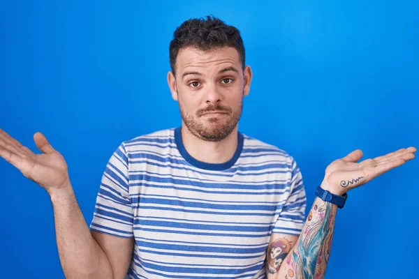 Young Hispanic Man Standing Blue Background Clueless Confused Expression Arms — Stok Foto