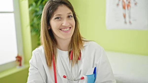 Joven Rubia Doctora Sonriendo Confiada Sentada Mesa Clínica —  Fotos de Stock
