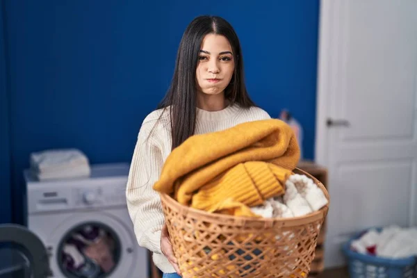 年轻的女人拿着洗衣篮 脸上带着滑稽的表情 喘气着脸颊 嘴被空气吹胀 — 图库照片