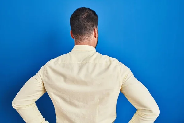 Pohledný Hispánec Stojí Nad Modrým Pozadím Dívá Dozadu Rukama Těle — Stock fotografie