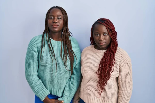 青い背景の上に立つ2人のアフリカ人女性は 真剣な表情でリラックスした カメラを見ているだけで — ストック写真