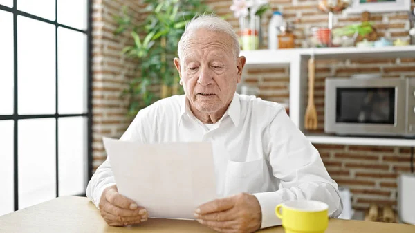 Oudere Grijsharige Man Leest Document Zittend Tafel Eetkamer — Stockfoto