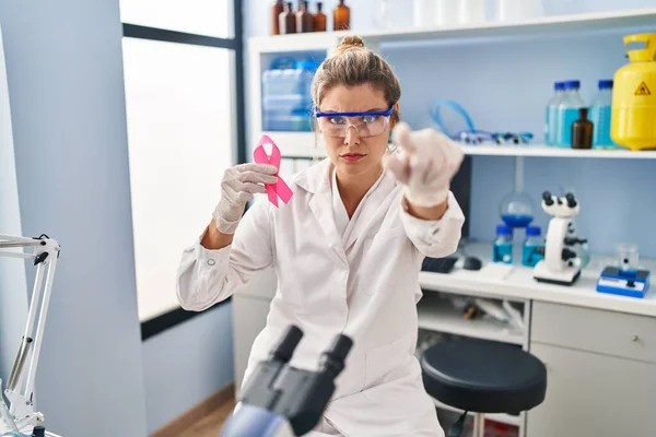 Молодая Женщина Работающая Научной Лаборатории Держит Розовую Ленту Указывая Пальцем — стоковое фото