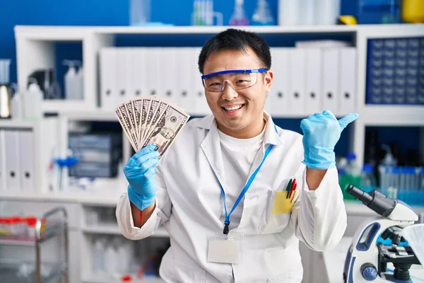 Молодой Китаец Работающий Научной Лаборатории Держит Деньги Указывая Пальцем Сторону — стоковое фото