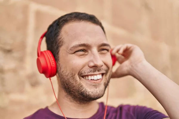 Jongeman Glimlachend Zelfverzekerd Luisteren Naar Muziek Geïsoleerde Bakstenen Achtergrond — Stockfoto