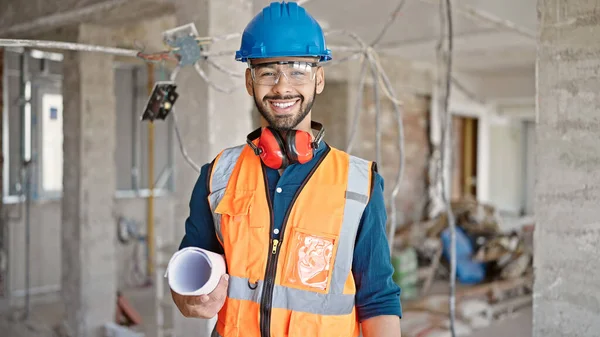 若いヒスパニック系の男性ビルダーは 建設現場で設計図と自信を持って立って笑顔 — ストック写真