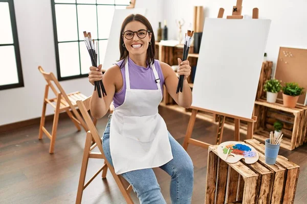 年轻美丽的惊慌失措的女画家微笑着 自信地在艺术工作室里拿着画笔 — 图库照片