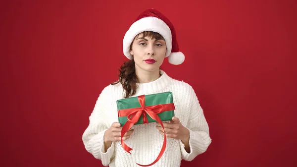 Νεαρή Καυκάσια Γυναίκα Σοβαρή Έκφραση Φορώντας Χριστουγεννιάτικο Καπέλο Κρατώντας Παρόν — Φωτογραφία Αρχείου