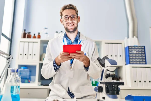 年轻科学家微笑着自信地在实验室使用触摸板 — 图库照片