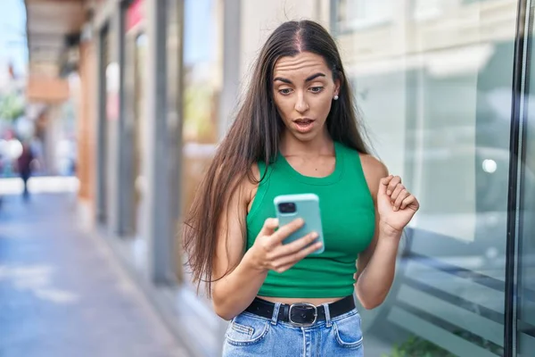 年轻美丽的惊慌失措的女人在街上用带有惊奇表情的智能手机 — 图库照片