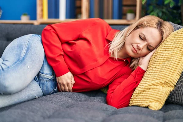 Young Blonde Woman Suffering Menstrual Pain Lying Sofa Home — 스톡 사진