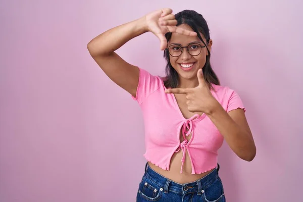 Латиноамериканская Молодая Женщина Стоящая Розовом Фоне Очках Улыбающаяся Делая Рамку — стоковое фото