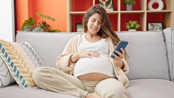 Genç Hamile Kadın Akıllı Telefon Kullanıyor Evde Karnına Dokunuyor — Stok fotoğraf
