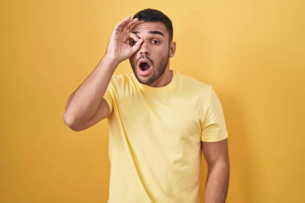 Homem Hispânico Jovem Sobre Fundo Amarelo Fazendo Gesto Chocado Com — Fotografia de Stock